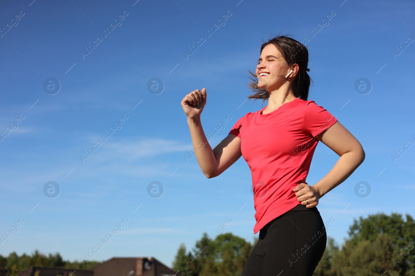 Photo of Young woman listening to music while running outdoors in morning. Space for text