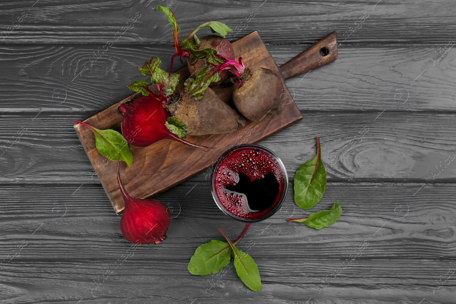 Photo of Fresh beet juice and raw vegetable on grey wooden table, flat lay