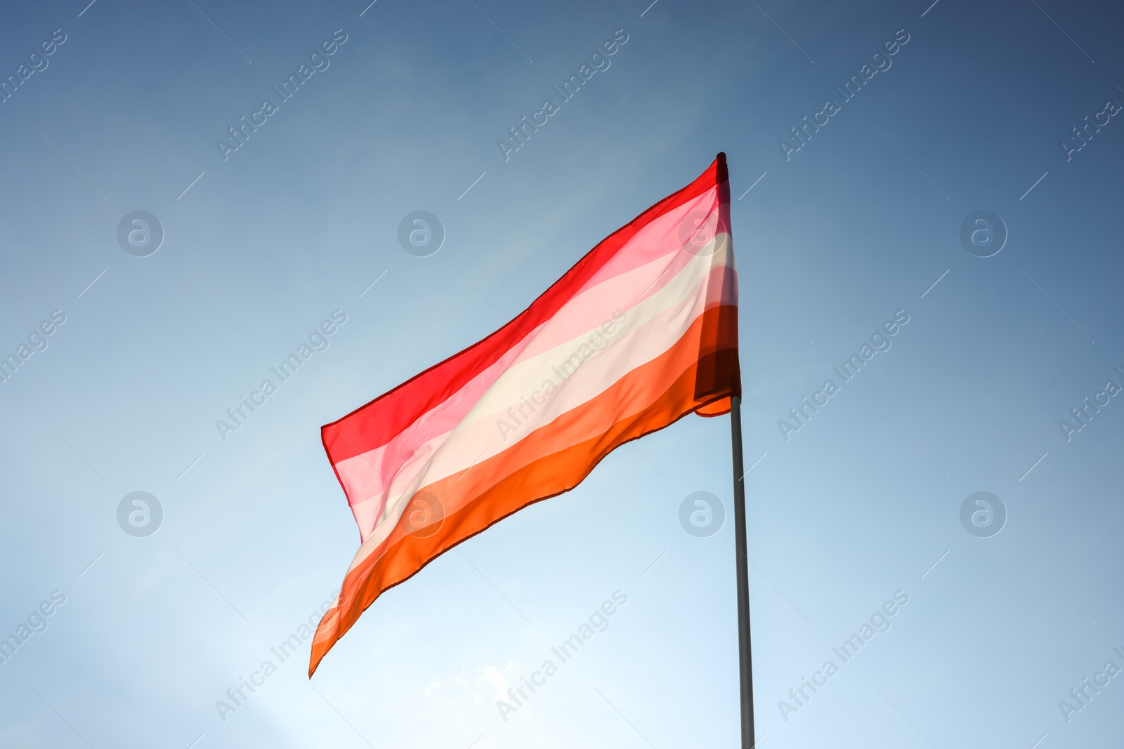 Photo of Bright lesbian flag fluttering against blue sky