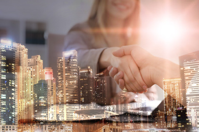 Image of Double exposure of night cityscape and business people shaking hands in office, closeup. Team work 