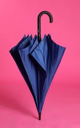 Photo of Stylish closed blue umbrella on pink background