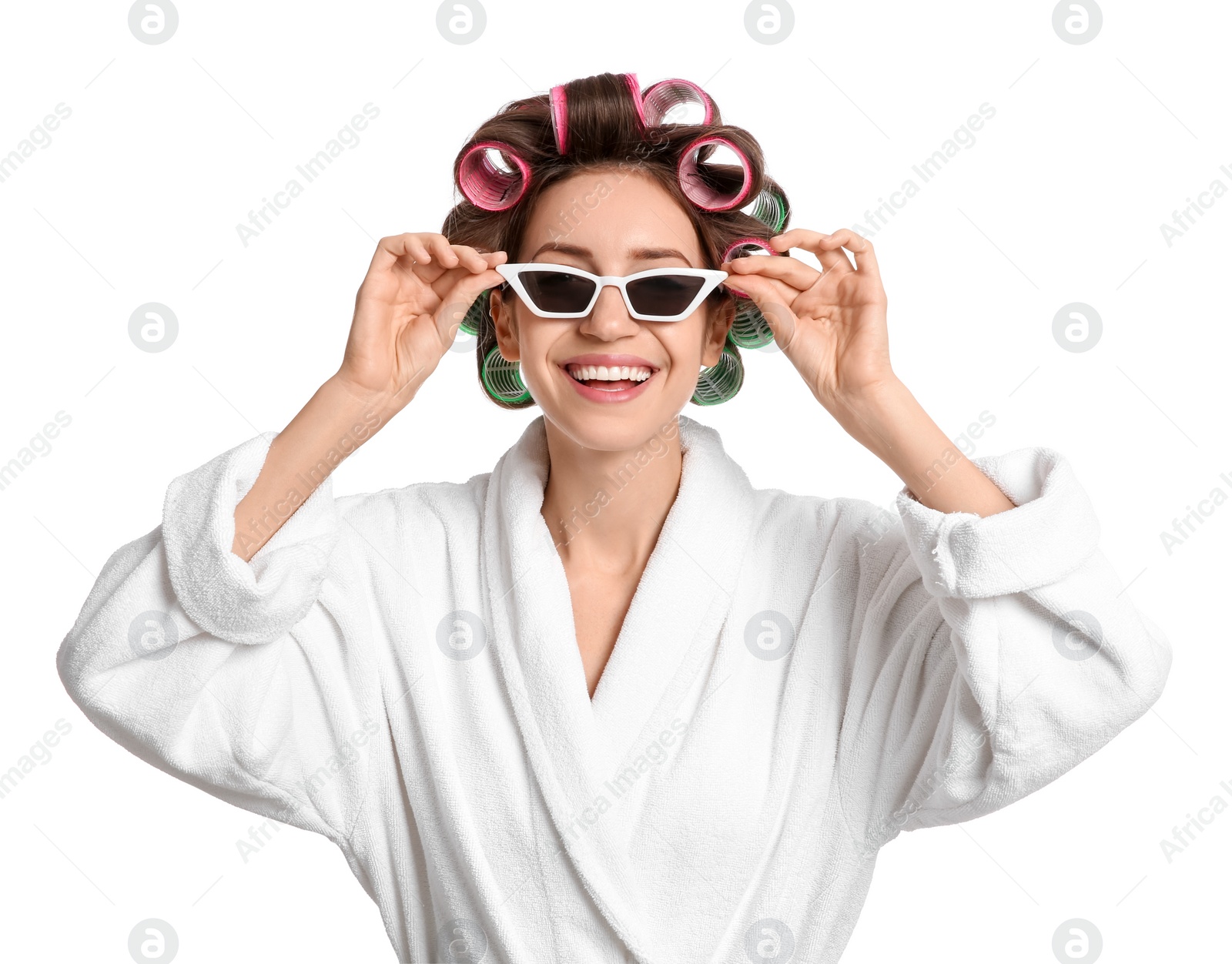 Photo of Beautiful young woman in bathrobe with hair curlers and sunglasses on white background