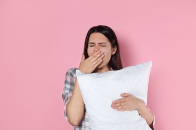 Photo of Sleepy young woman with soft pillow yawning on pink background