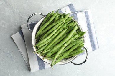 Photo of Fresh green beans in colander on grey marble table, top view