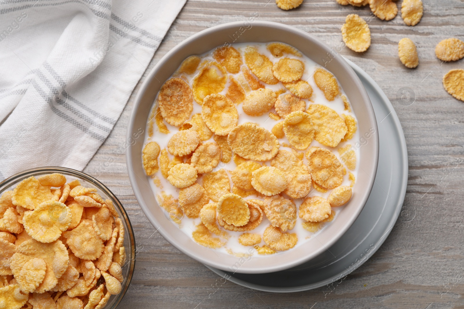 Photo of Tasty cornflakes with milk in bowl on wooden table, flat lay