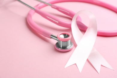 Photo of Pink ribbon and stethoscope on color background, closeup. Breast cancer concept