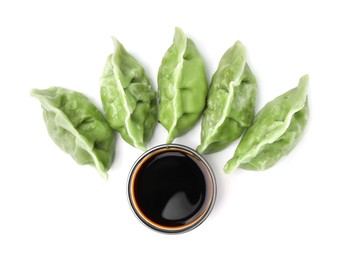 Delicious green dumplings (gyozas) and soy sauce isolated on white, top view