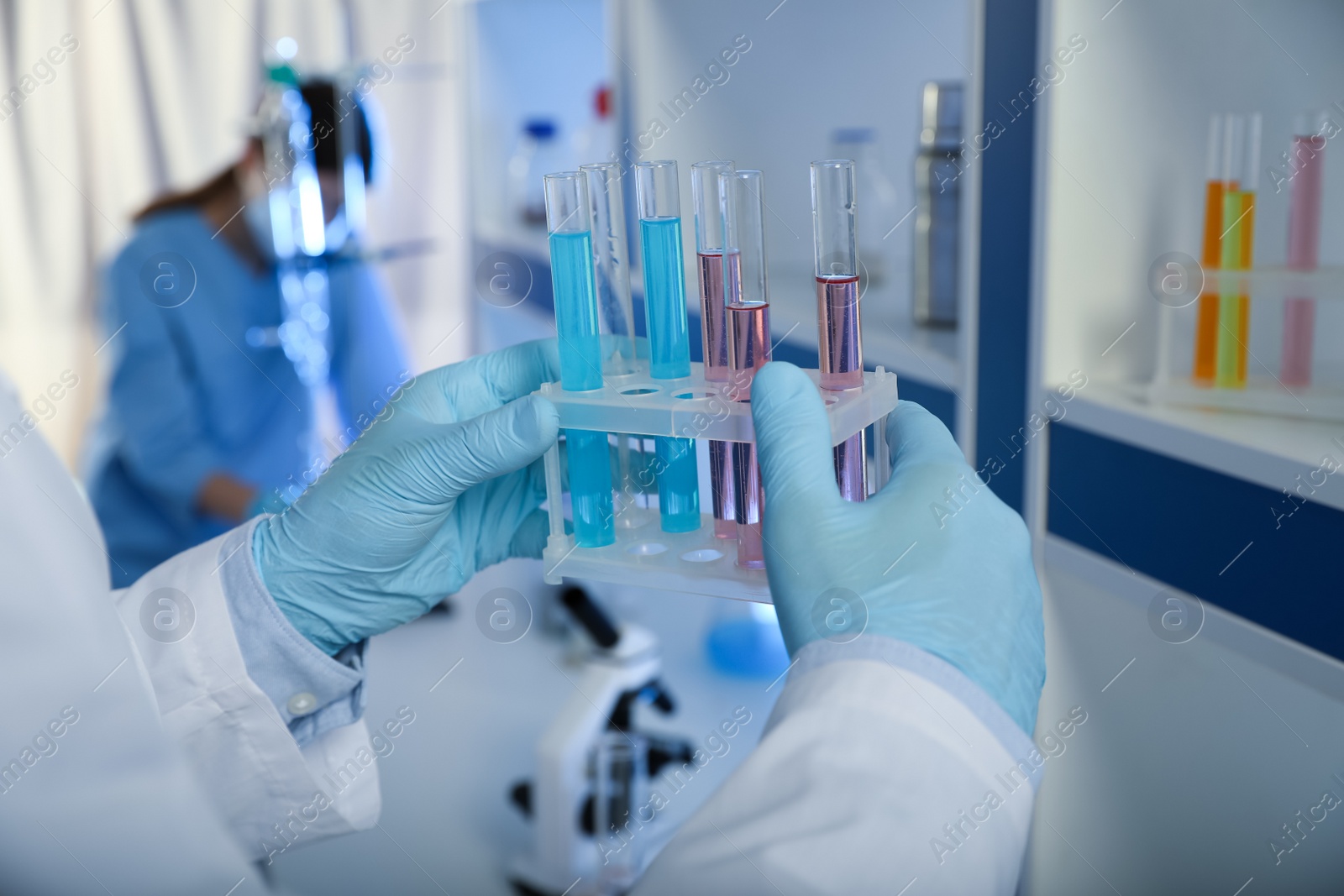 Photo of Scientist holding test tubes with liquid indoors, closeup. Laboratory analysis