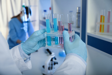 Photo of Scientist holding test tubes with liquid indoors, closeup. Laboratory analysis