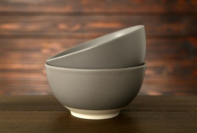 Photo of Stylish empty ceramic bowls on wooden table. Cooking utensils