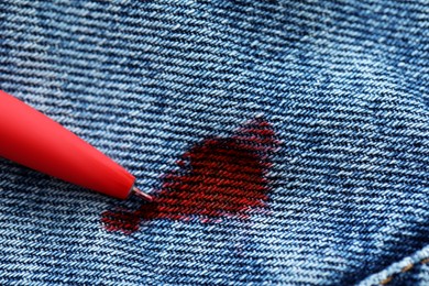 Photo of Pen and stain of red ink on jeans, closeup