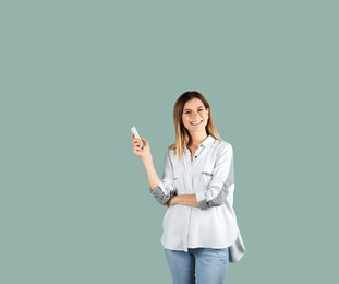 Woman with air conditioner remote on color background