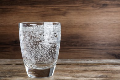 Photo of Glass of soda water on wooden table. Space for text