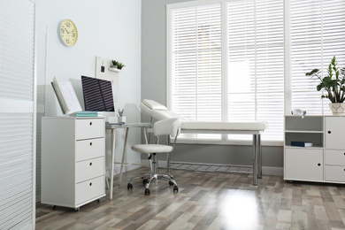 Photo of Modern medical office interior with computer and examination table