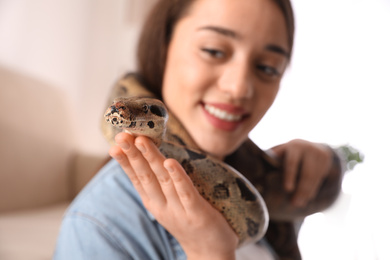 Young woman with her boa constrictor at home, focus on hand