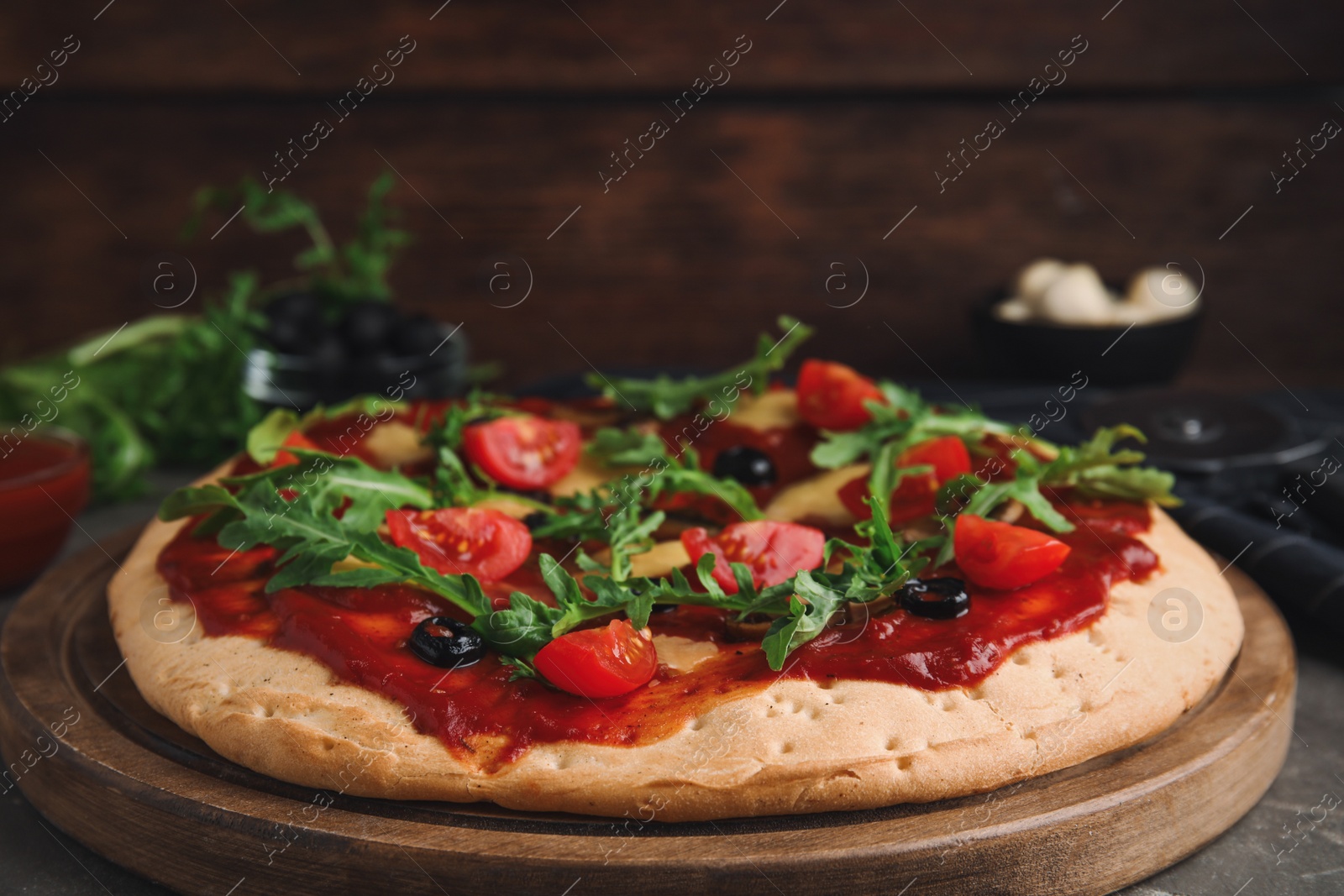 Photo of Pita pizza with cheese, olives, tomatoes and arugula on grey table, closeup