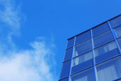 Photo of Modern office building with tinted windows against blue sky