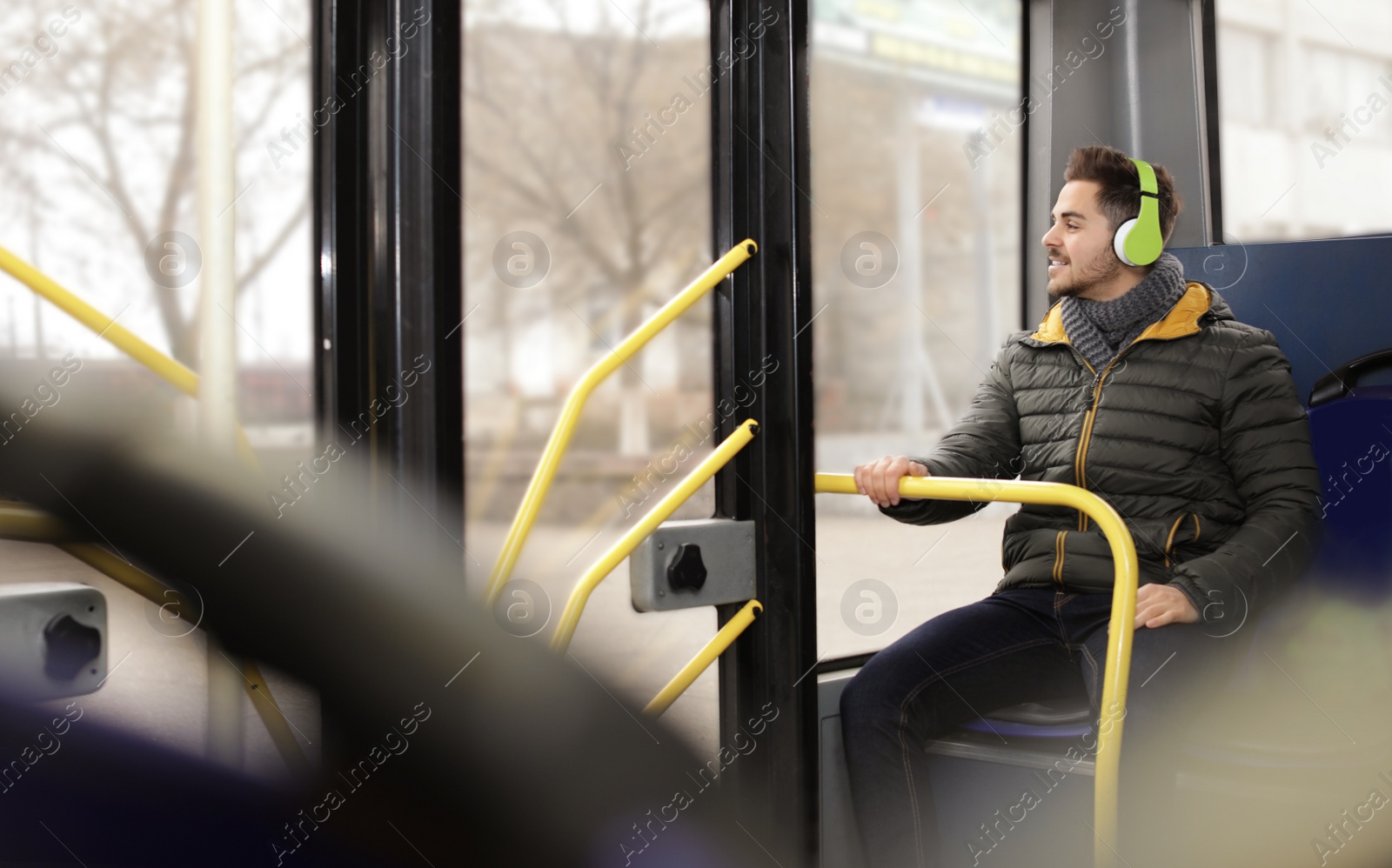 Photo of Young man listening to music with headphones in public transport