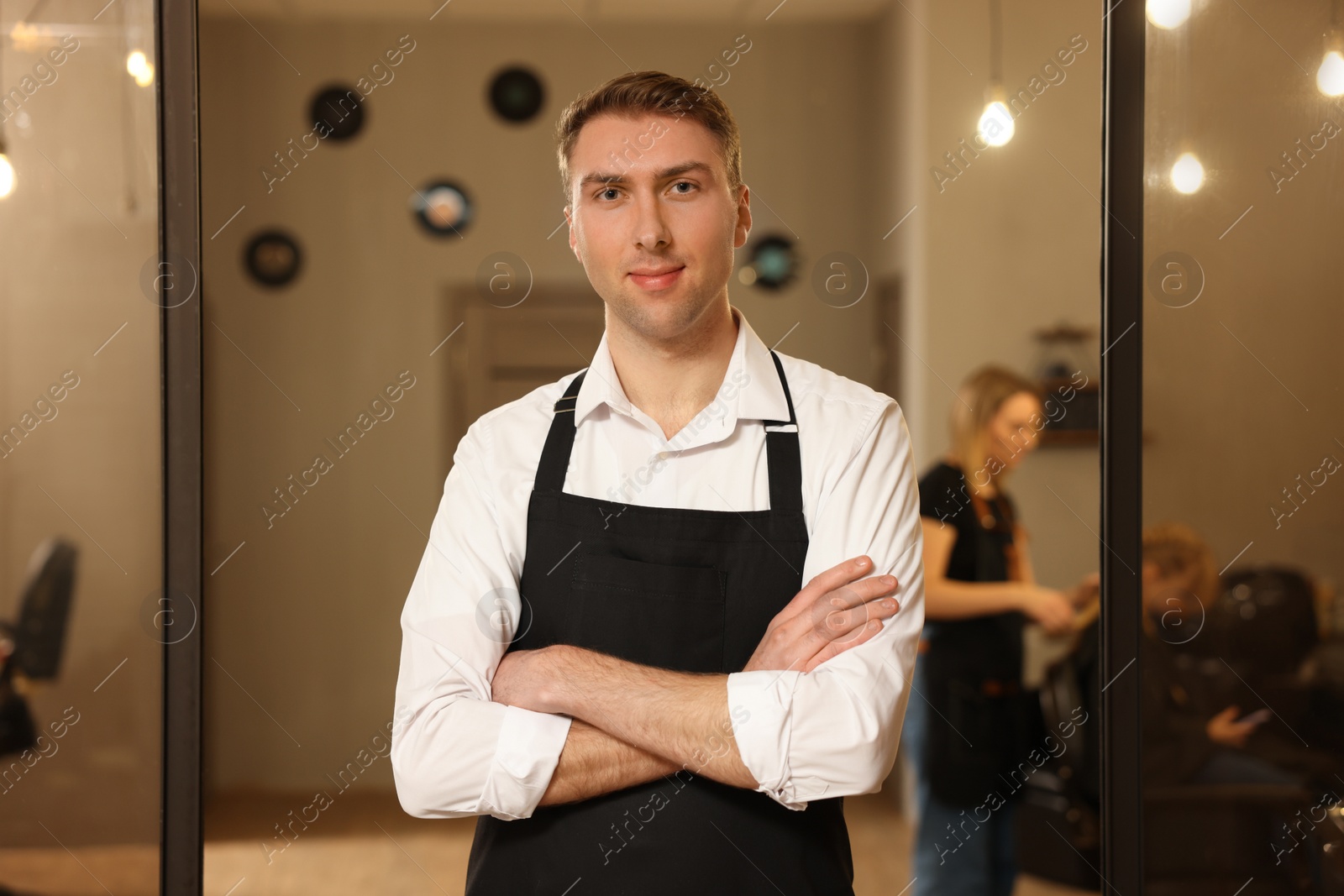 Photo of Portrait of professional hairdresser wearing apron in beauty salon