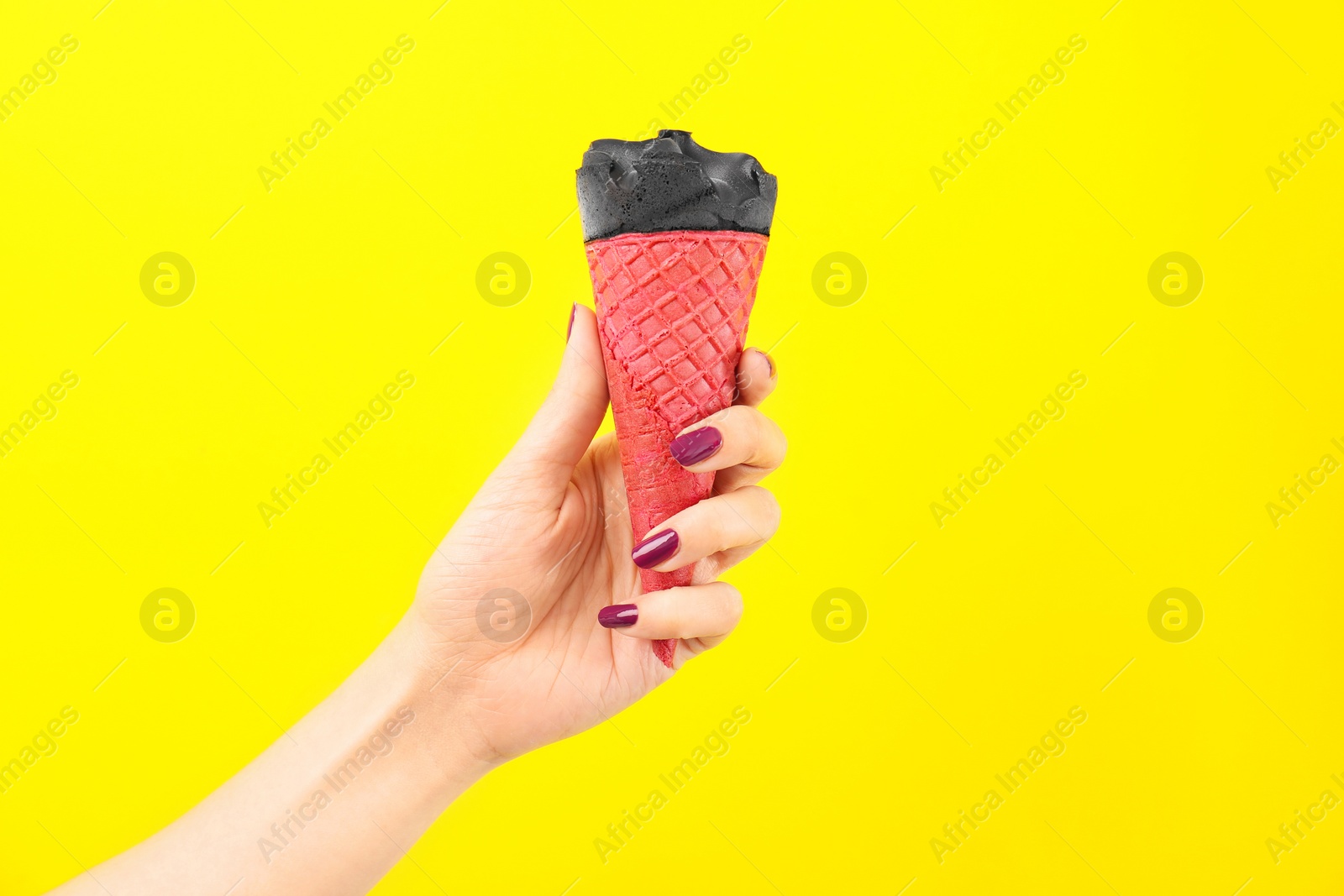 Photo of Woman holding yummy ice cream on color background. Focus on hand