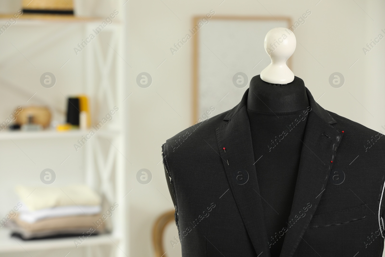 Photo of Mannequin with unfinished jacket in tailor shop, closeup. Space for text