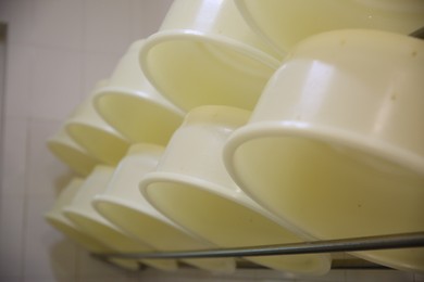 Photo of Clean cheese moulds on rack at dairy factory, closeup