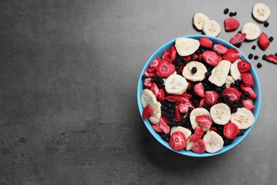 Bowl of dried fruits on grey table, top view. Space for text