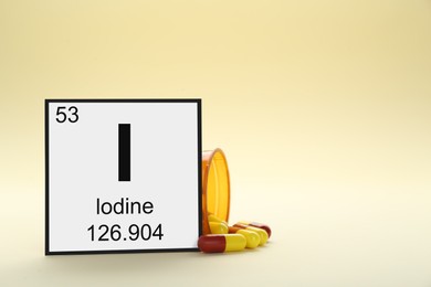 Photo of Card with iodine element, jar and pills on beige background. Space for text