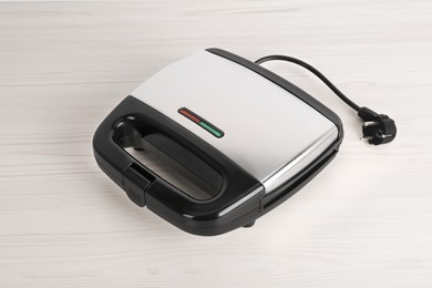 Photo of Closed electric sandwich maker on white wooden table