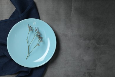 Elegant plate with twig and napkin on dark grey table, top view. Space for text