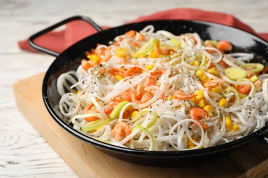 Photo of Frying pan with rice noodles, shrimps and vegetables on table