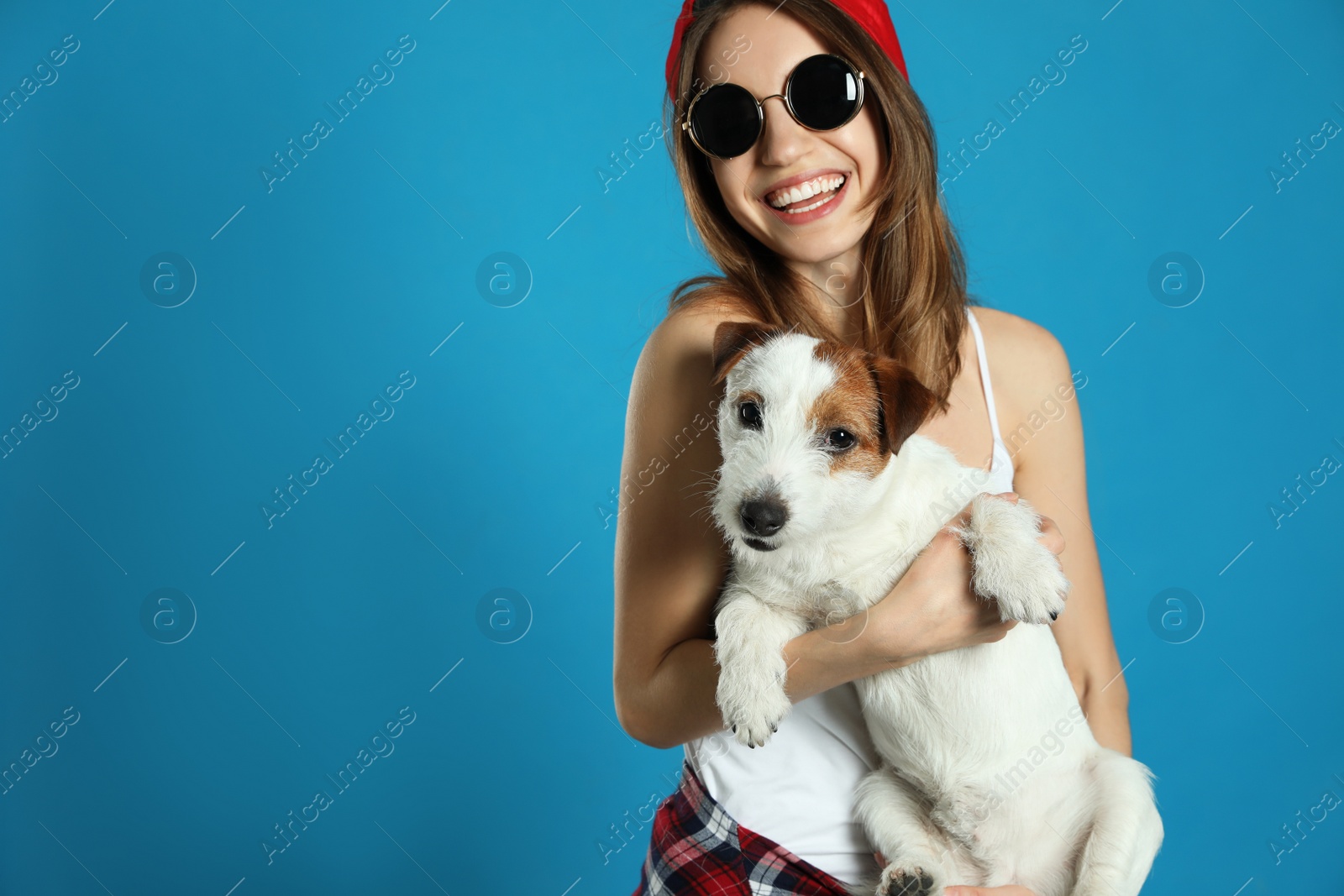 Photo of Young woman with her cute Jack Russell Terrier on light blue background, space for text. Lovely pet