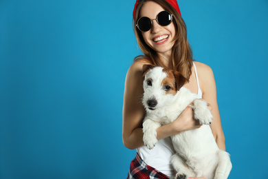 Photo of Young woman with her cute Jack Russell Terrier on light blue background, space for text. Lovely pet