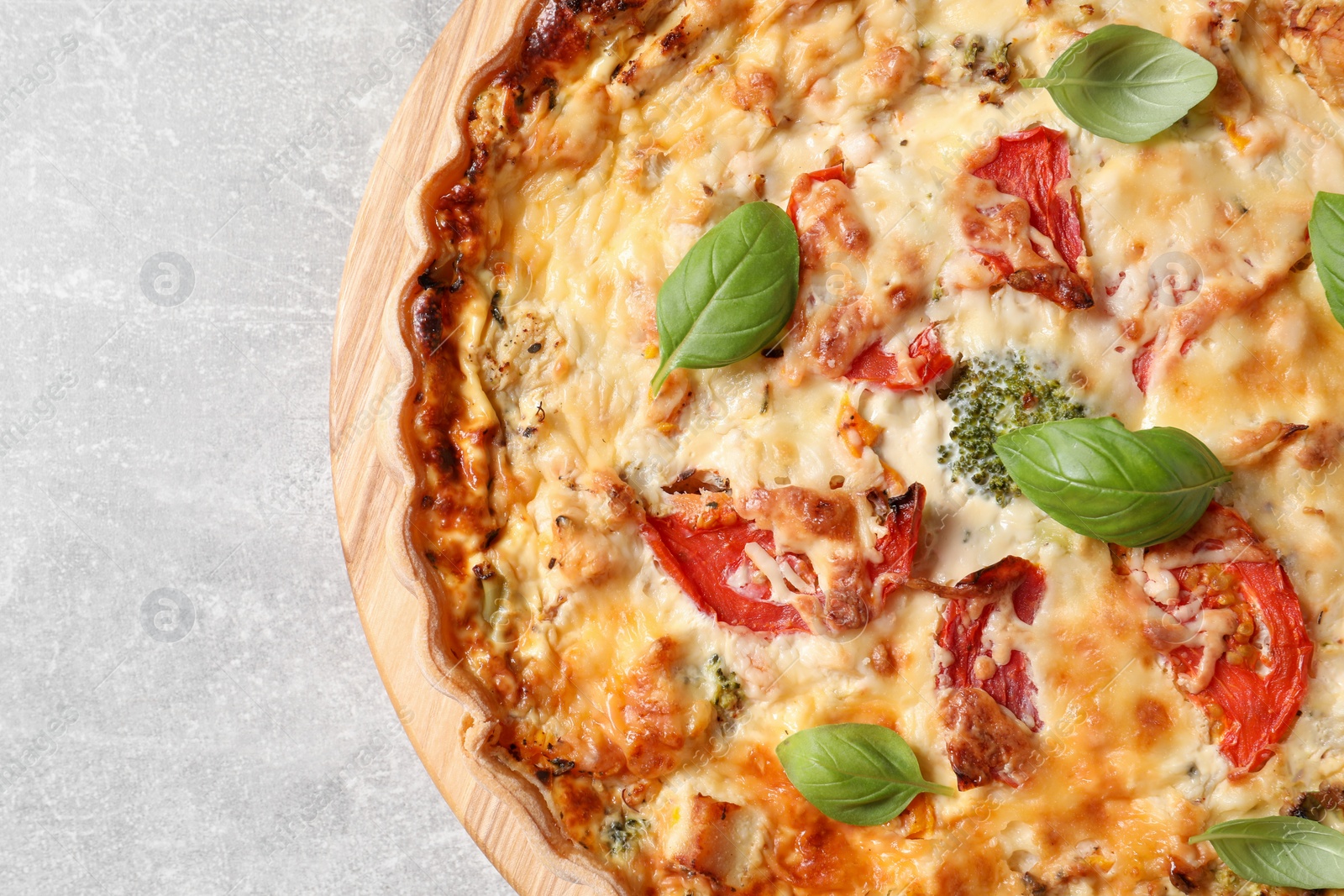 Photo of Tasty quiche with tomatoes, basil and cheese on light table, top view