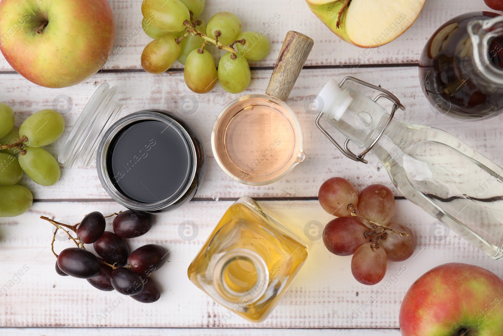 Photo of Different types of vinegar and ingredients on wooden table, flat lay