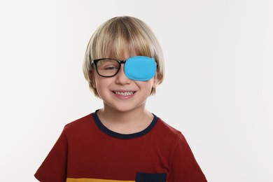 Photo of Happy boy with nozzle on glasses for treatment of strabismus against white background