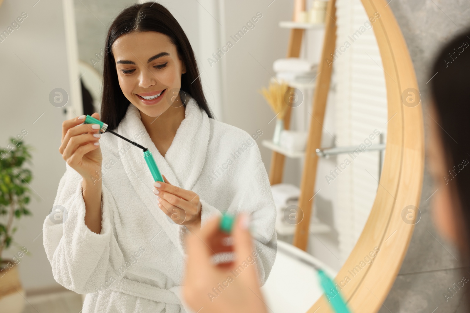 Photo of Beautiful young woman with mascara in bathroom