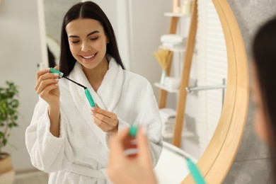 Beautiful young woman with mascara in bathroom