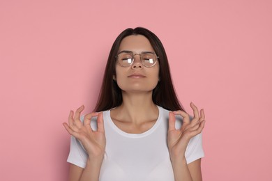 Young woman meditating on pink background. Zen concept