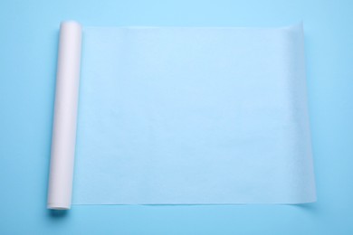 Photo of Roll of baking paper on light blue background, top view