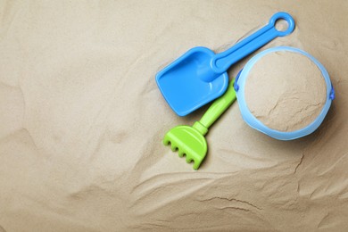Plastic toy set with shovel on sand, flat lay