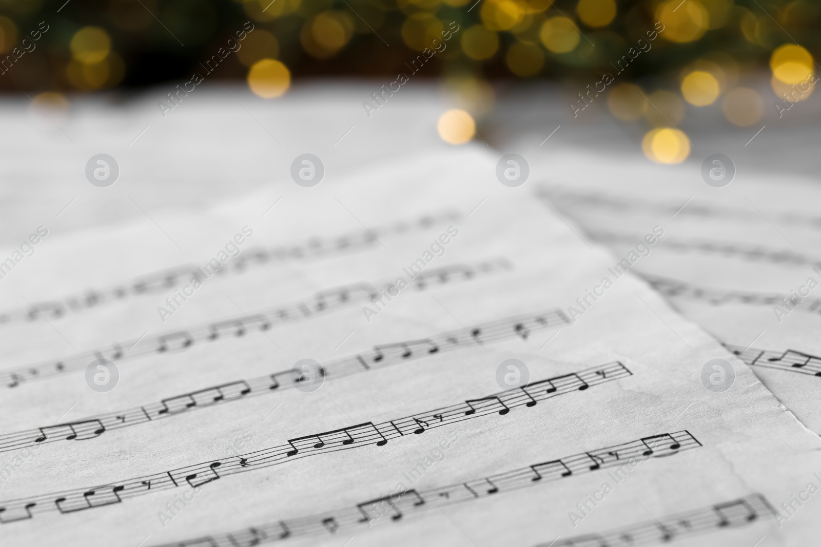 Photo of Closeup view of note sheets against blurred lights. Christmas music