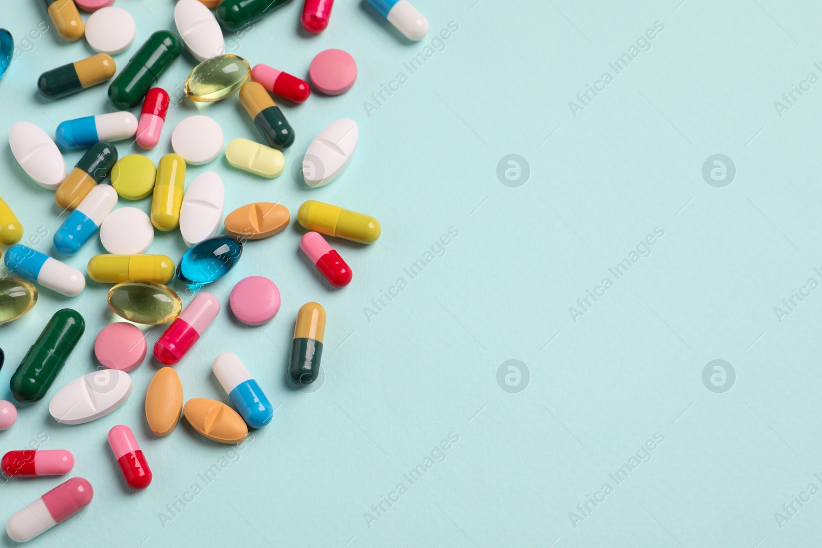 Photo of Many different pills on light turquoise background, above view. Space for text