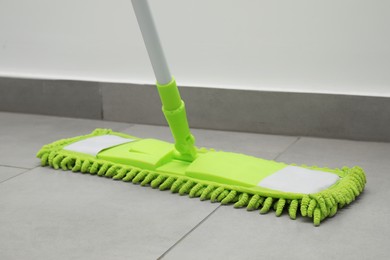 Photo of Cleaning grey tiled floor with microfiber mop, closeup