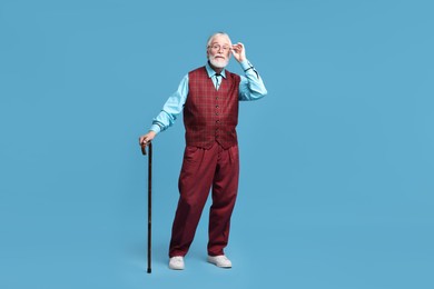 Senior man with walking cane on light blue background