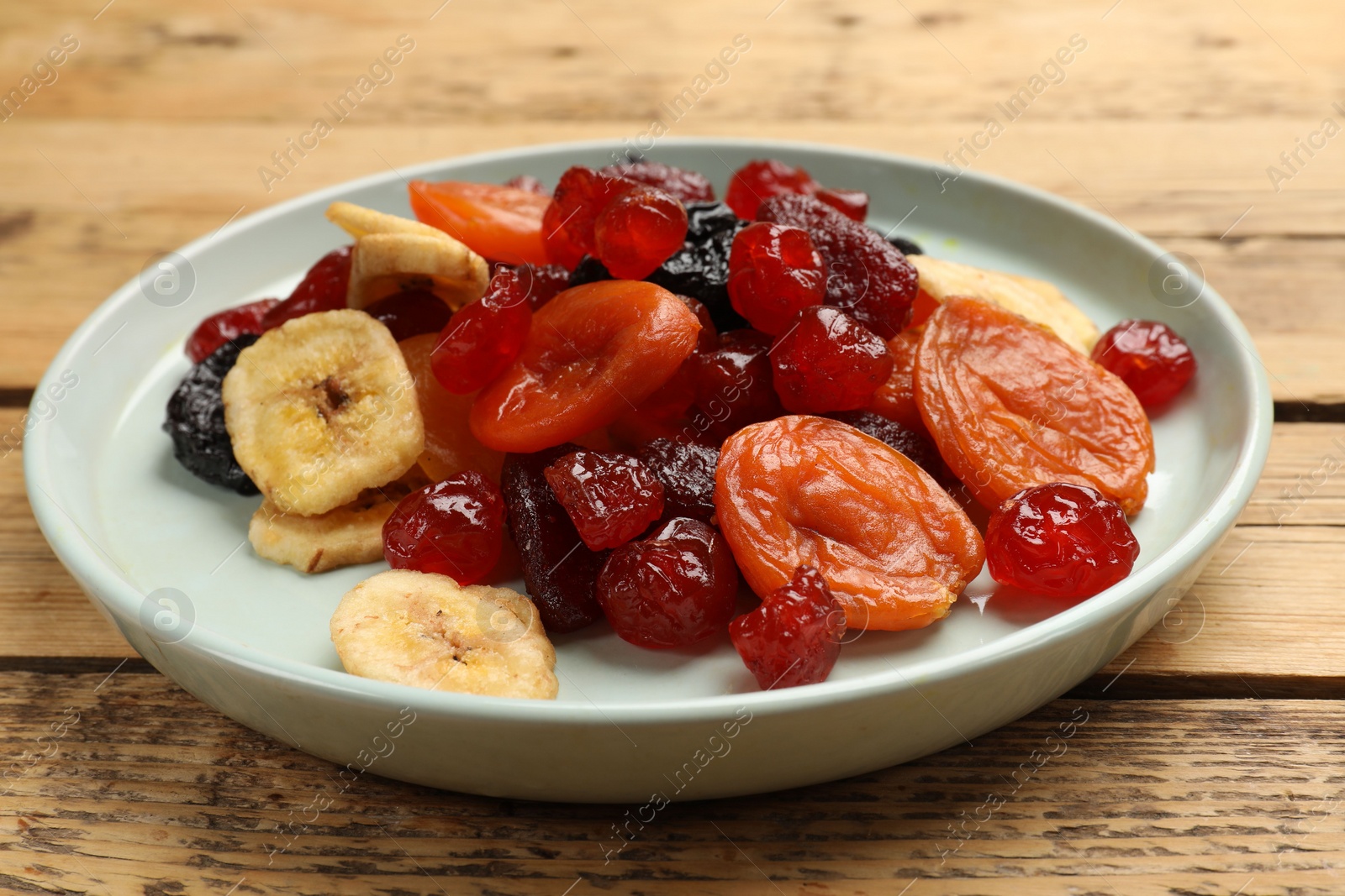 Photo of Mix of delicious dried fruits on wooden table, closeup