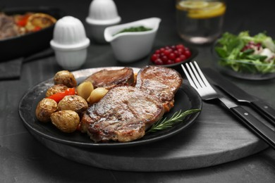 Photo of Tasty beef tongue pieces, rosemary and potatoes on grey table, closeup