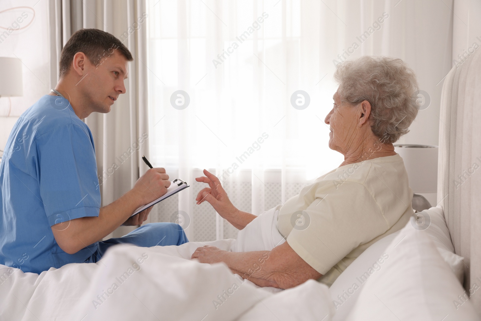 Photo of Caregiver examining senior woman in bedroom. Home health care service