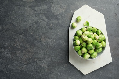 Board with bowl of Brussels sprouts on grey background, top view. Space for text