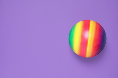Photo of New bright kids' ball on purple background, top view. Space for text